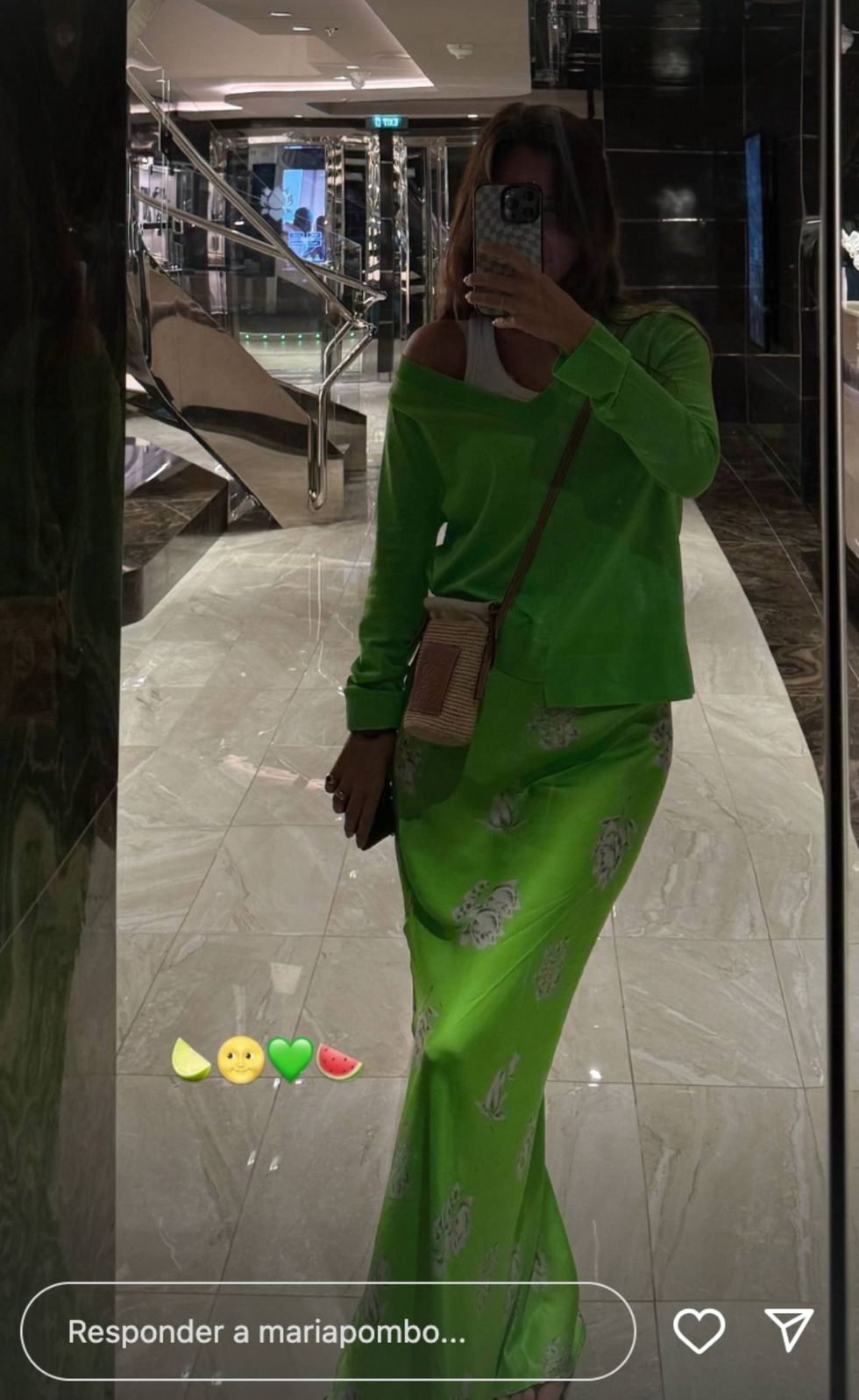 a person in a green dress taking a selfie in a mirror