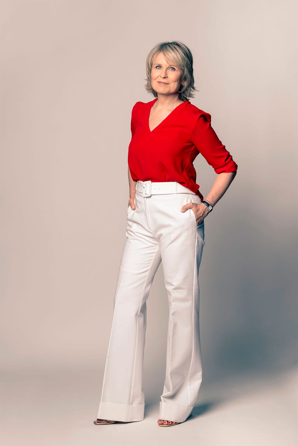 María Rey con suéter rojo y pantalón de campana blanco 