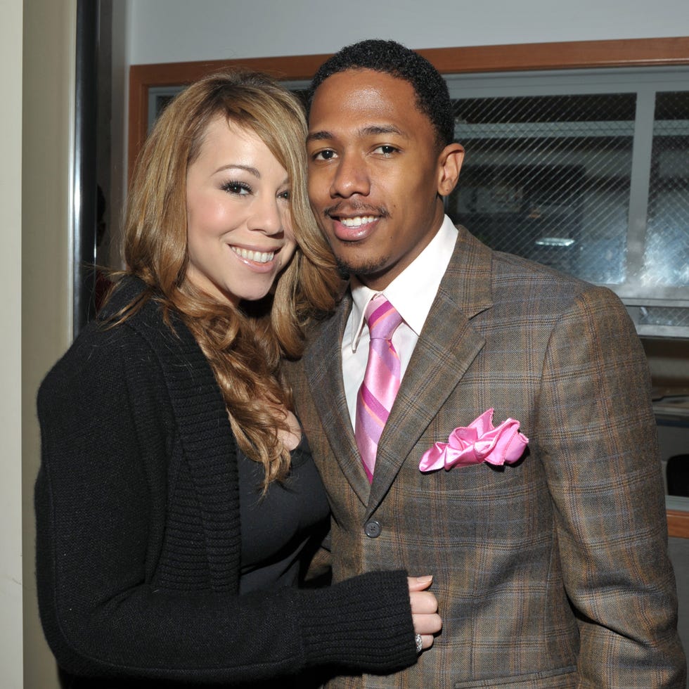 mariah carey hugs nick cannon as they both stand and smile at the camera