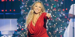 mariah carey pointing out toward the audience while singing in front of christmas decorations