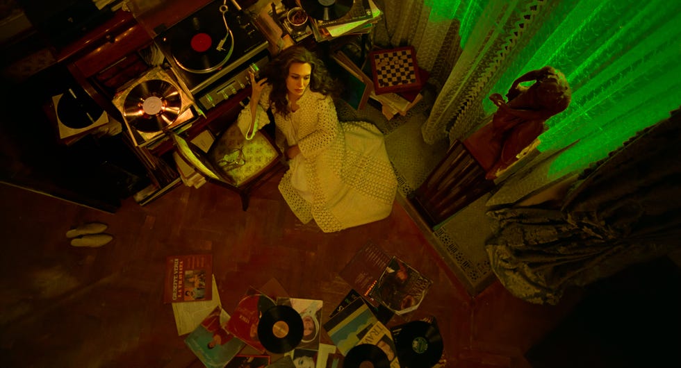 angelina jolie as maria callas sitting alone with records piled around her in a small room