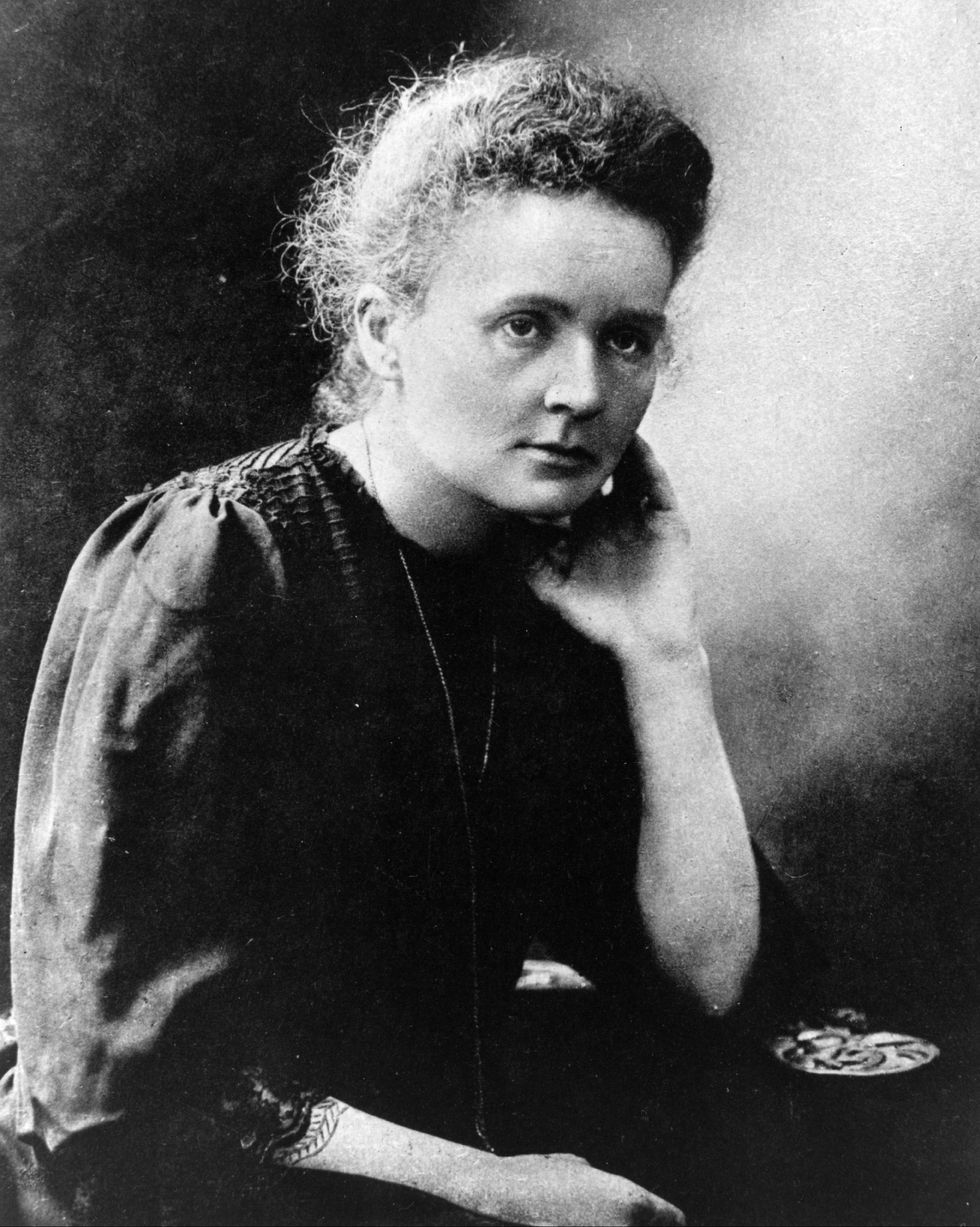 Marie Curie sentada con la cabeza apoyada en la mano izquierda en una fotografía.