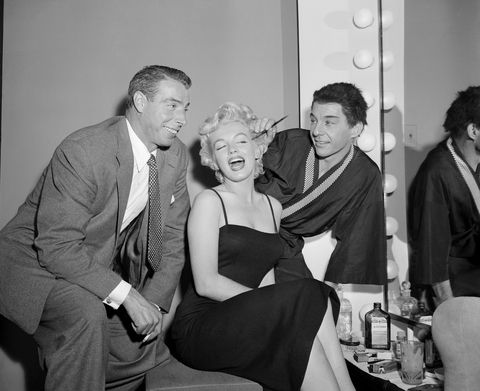 actor david wayne applies makeup to marilyn monroe while her husband joe dimaggio looks on the couple had been in the audience at the martin beck theater to see "the teahouse of the august moon", which wayne stars in