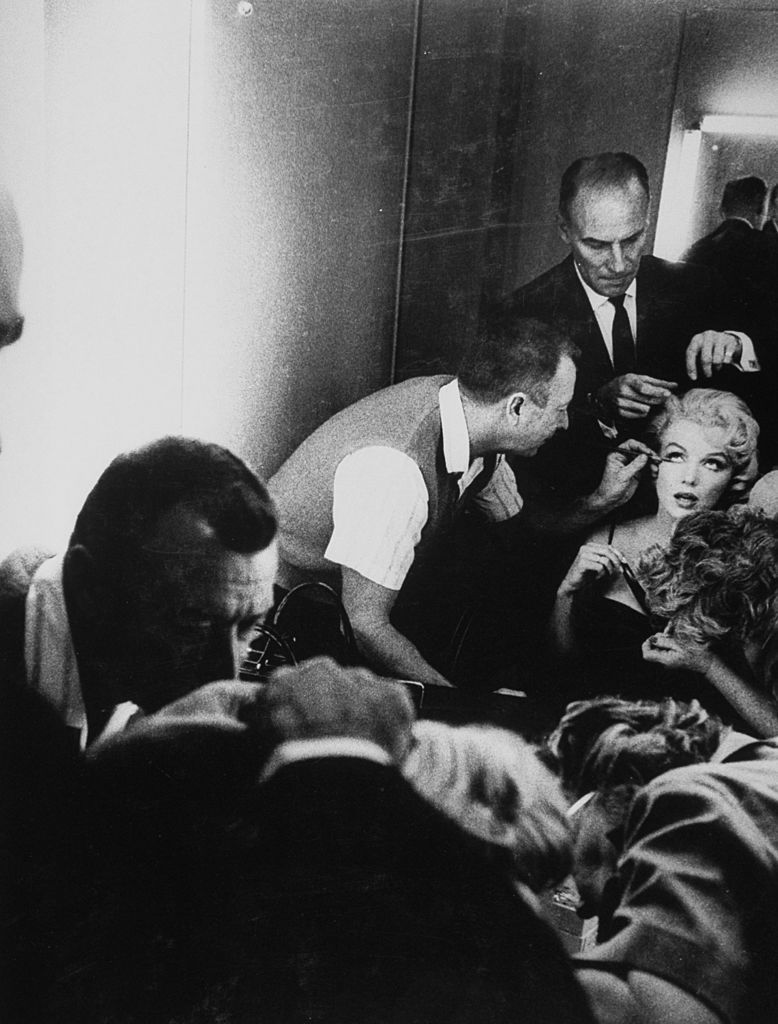 chief hairdresser for mgm sydney guilaroff, stylist for the stars, combing actress marilyn monroes hair as makeup man works on her eyes in dressing room during filming of the movie lets make love at mgm studios    photo by john brysongetty images