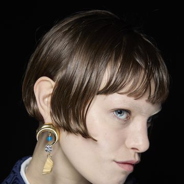 a woman with a blue shirt and earrings
