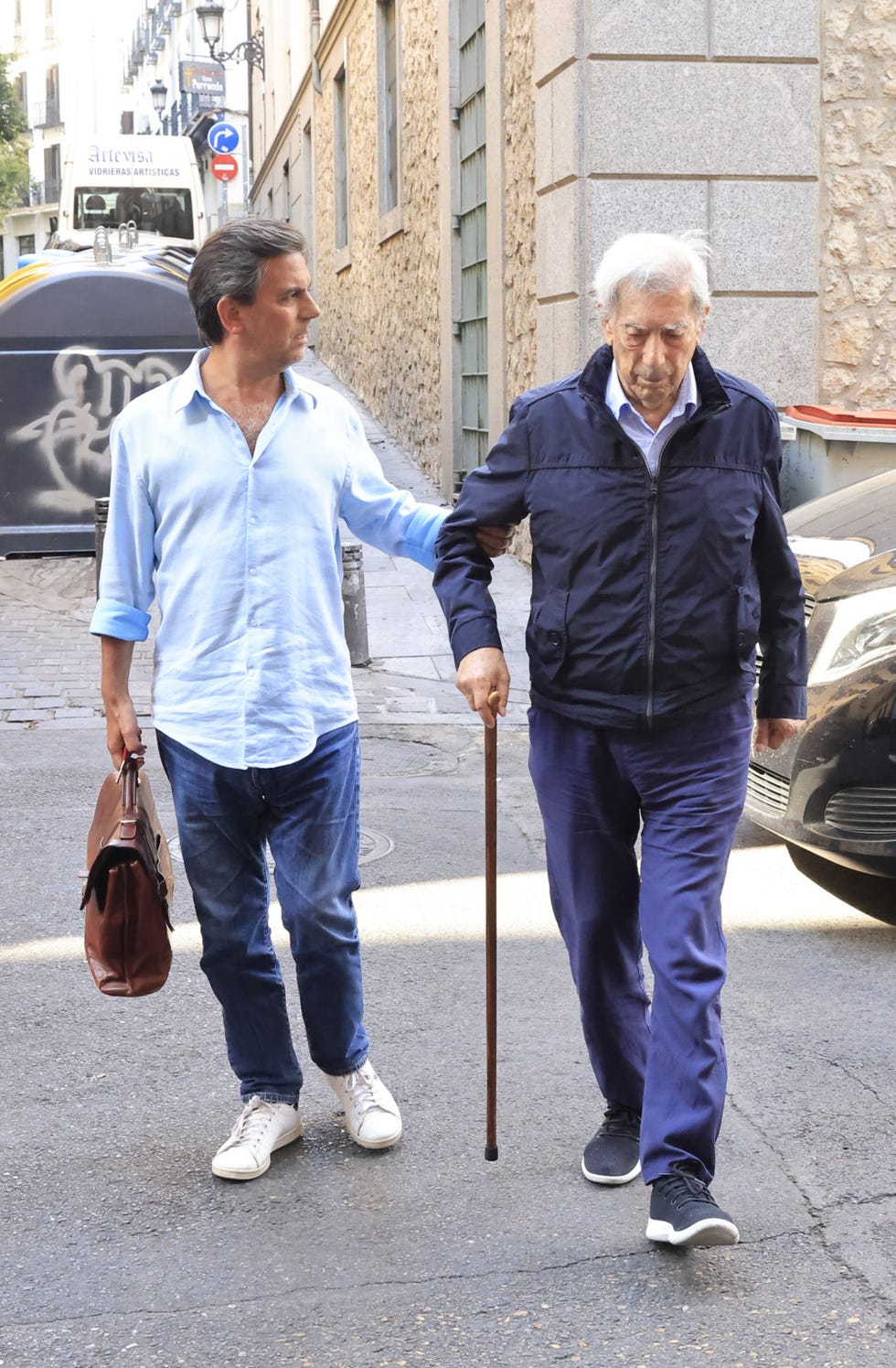 el escritor camina con un baston y ayudado por su hijo