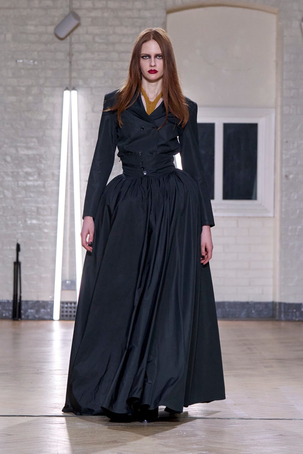 Fashion model showcasing a dark gown in a minimalist setting