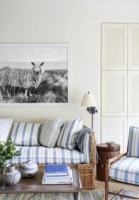 a wicker sofa has blue and white striped cushions and books stacked on a coffee table