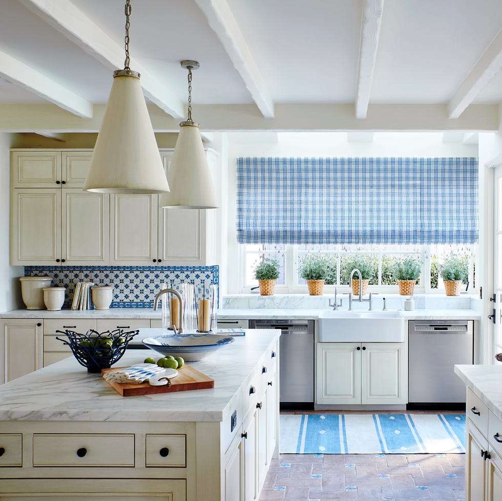 an off white kitchen with blue and white backsplash and rug and window treatment