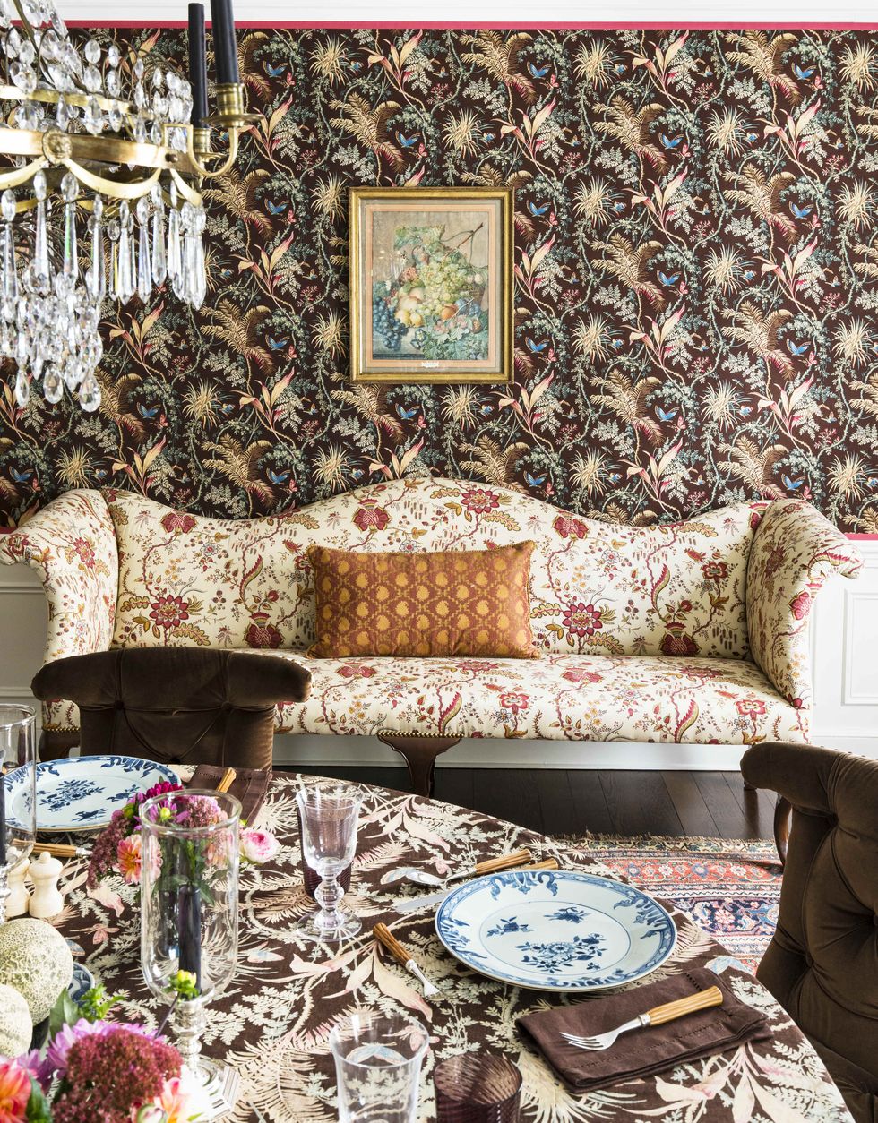 a patterned sofa sits against a wallpapered wall in the dining room