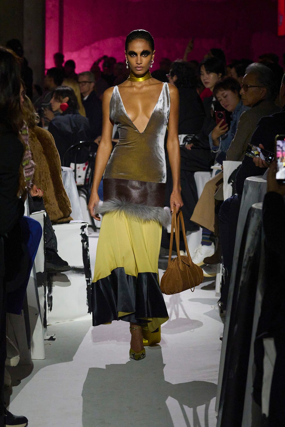 Model walking on runway wearing a striking multicolored outfit
