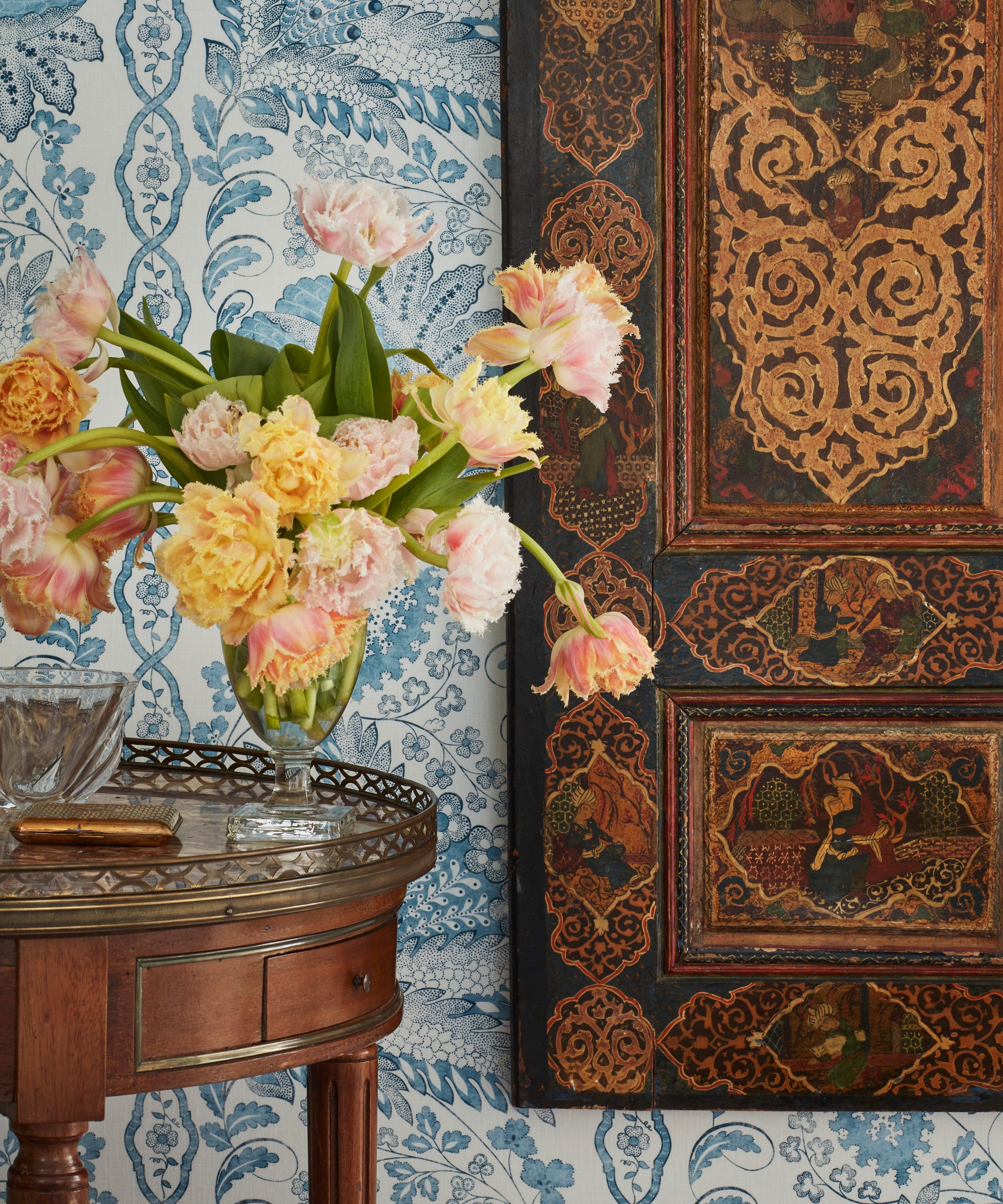 floral arrangement on an antique table with an antique door hung on the wall