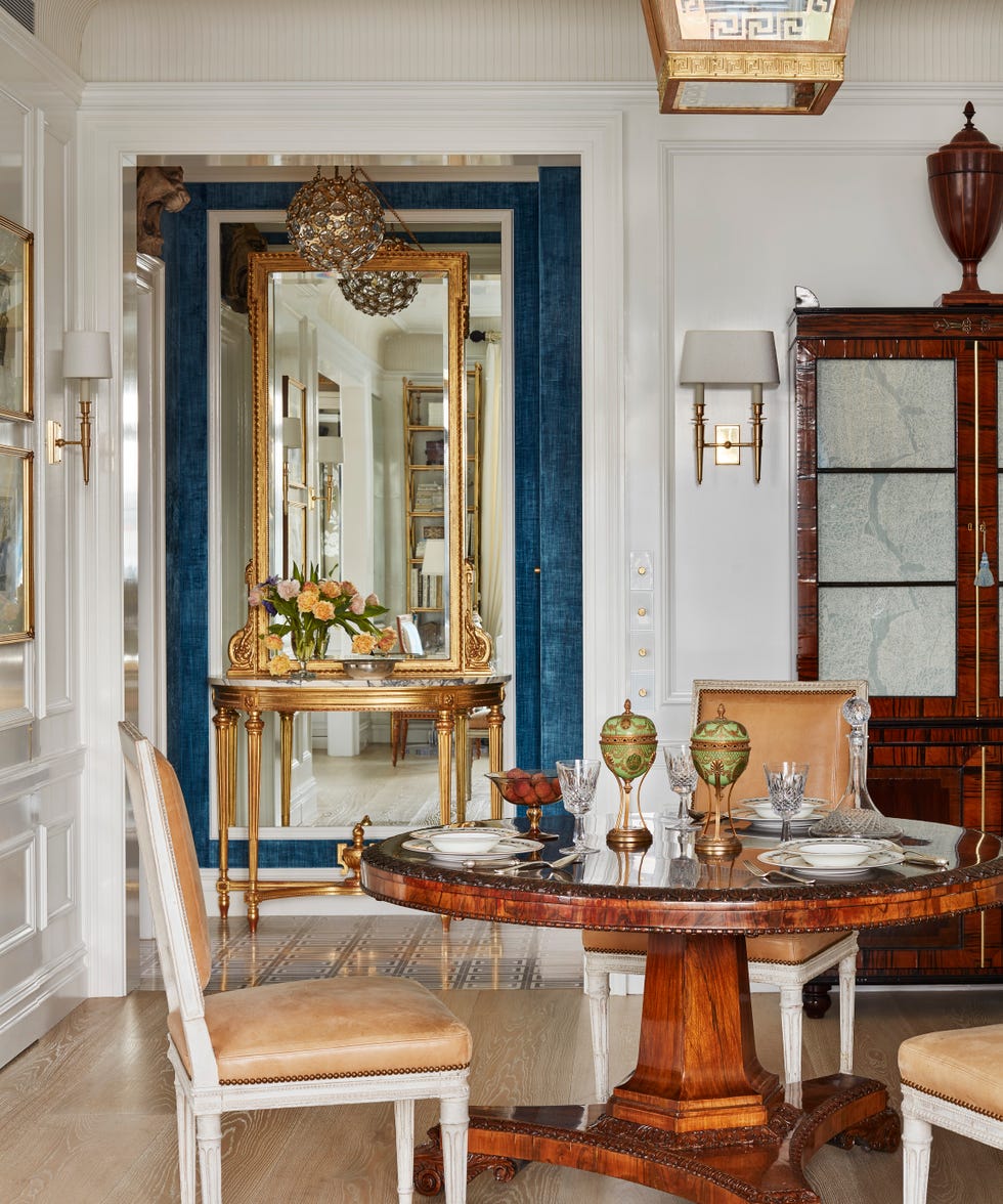 wood pedestal dining table with tan upholstered chairs around it