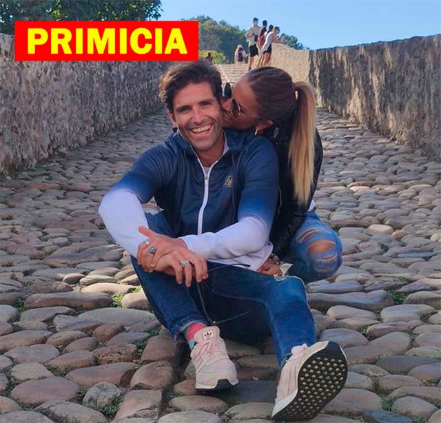 a man and woman sitting on a rock wall