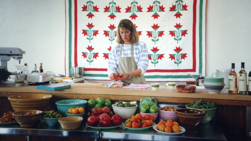 A woman prepares food in a kitchen displaying a selection of fresh produce