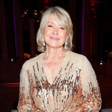 martha stewart smiling for a photographer in front of a decorative railing