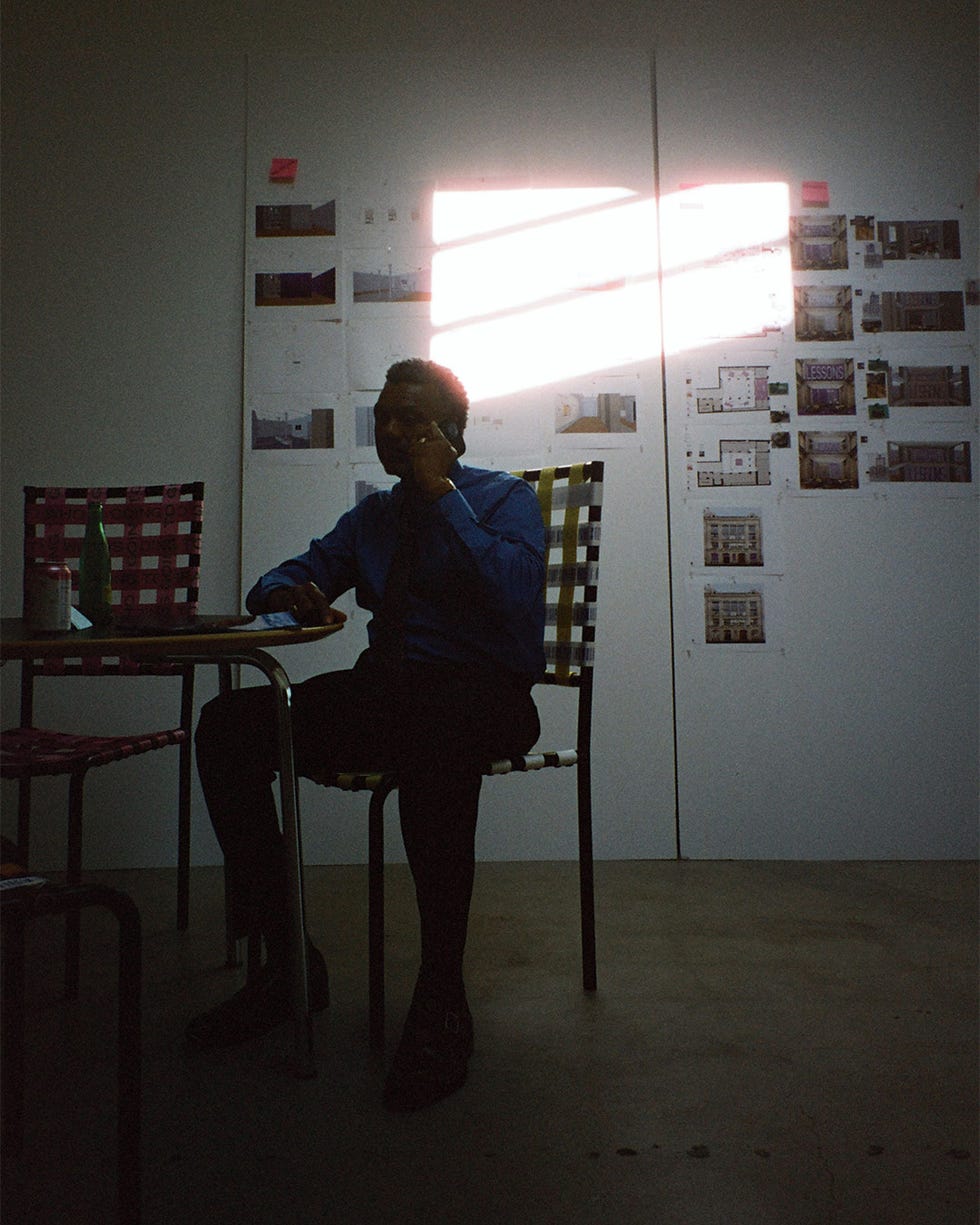 a person sitting at a table in front of a wall covered in printed materials