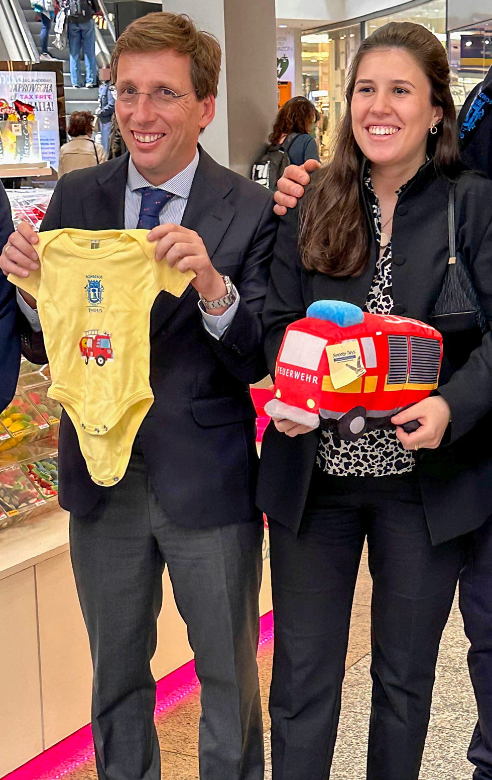 el alcalde de madrid y su esposa, embarazada, posan con un body y un peluche regalo de los bomberos de madrid