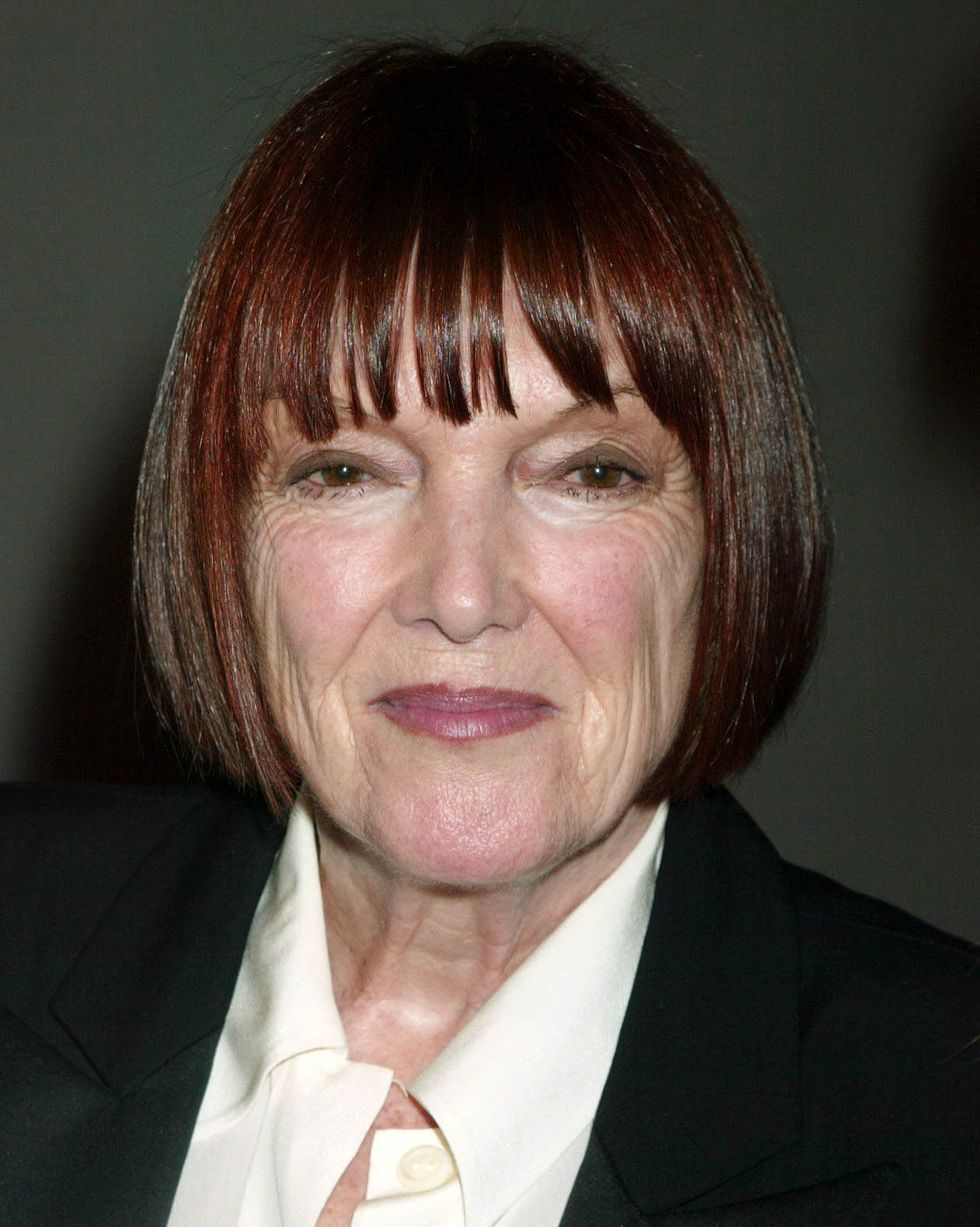 fashion icon mary quant smiles at the camera, sporting her signature vidal sassoon bob, a dark jacket and a cream colored collared shirt