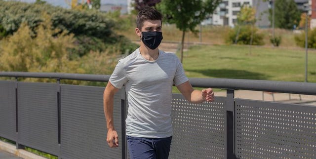 un chico camina por la calle con una mascarilla de decathlon