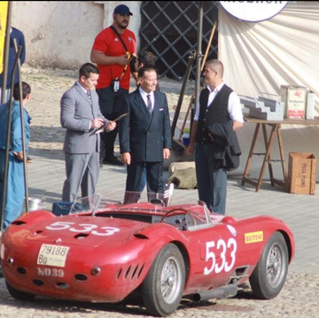 a group of people standing around a red race car