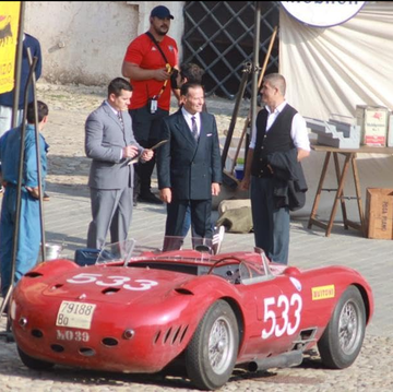 a group of people standing around a red race car