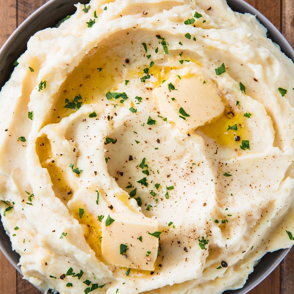 mashed potatoes in a bowl topped with a pat of butter and chopped parsley