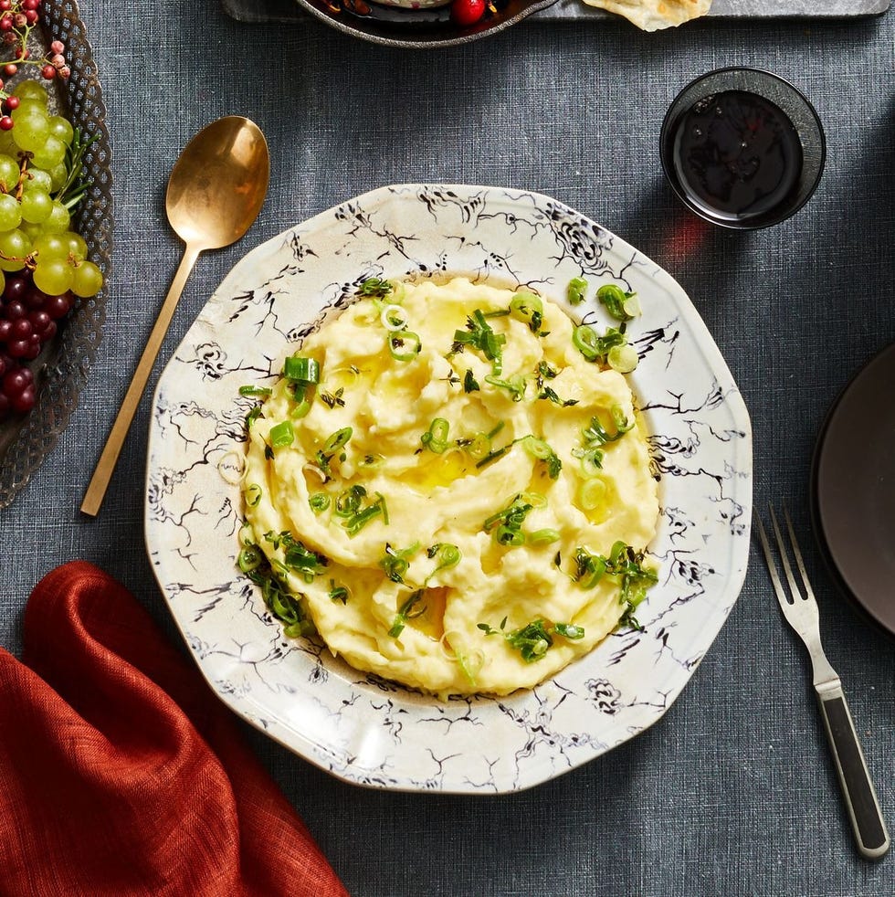 mashed potatoes with sliced scallions on top in a white bowl