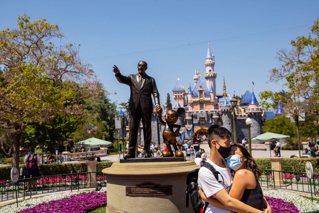 https://hips.hearstapps.com/hmg-prod/images/masked-couple-poses-for-photos-in-front-of-a-statue-of-walt-news-photo-1621870418.jpg?crop=0.668xw:1.00xh;0.236xw,0&resize=1200:*