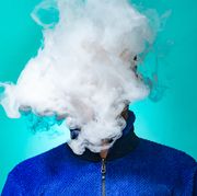 a masked man smoking vape and exhaling