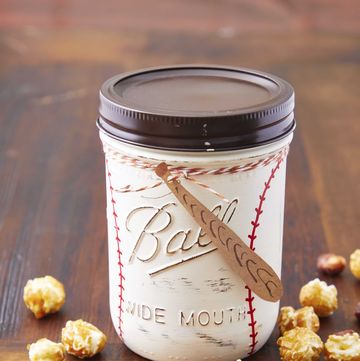 a mason jar painted to look like a baseball filled with popcorn