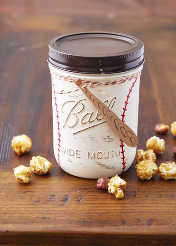 a mason jar painted to look like a baseball filled with popcorn