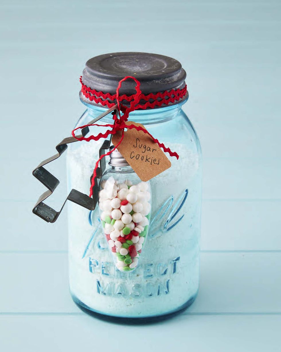 a mason jar filled with dry cookie mix with a cookie cutter attached to the outside of the jar