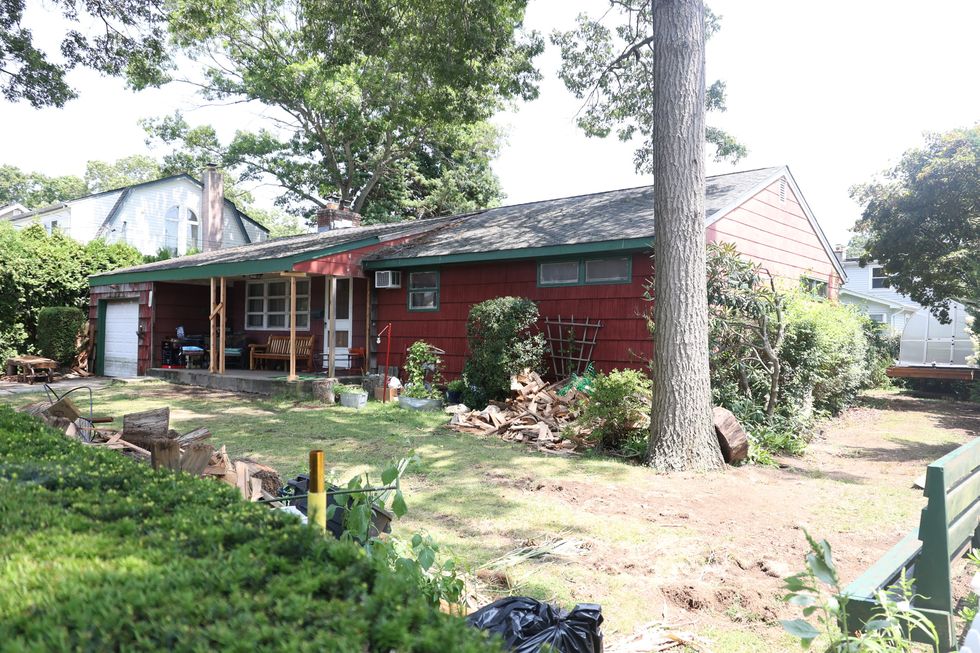 a red wooden ranch house with a grass yard