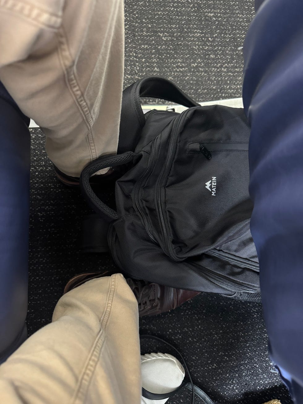 closeup of legs and a backpack on a train or airplane seat