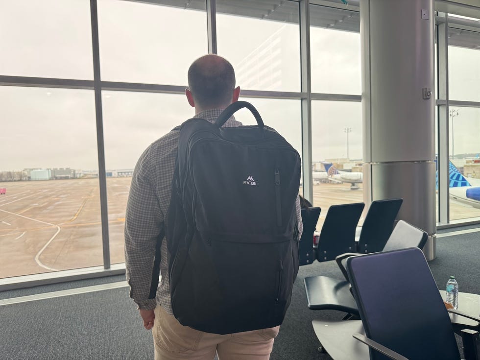 person standing at an airport window looking out over the runway