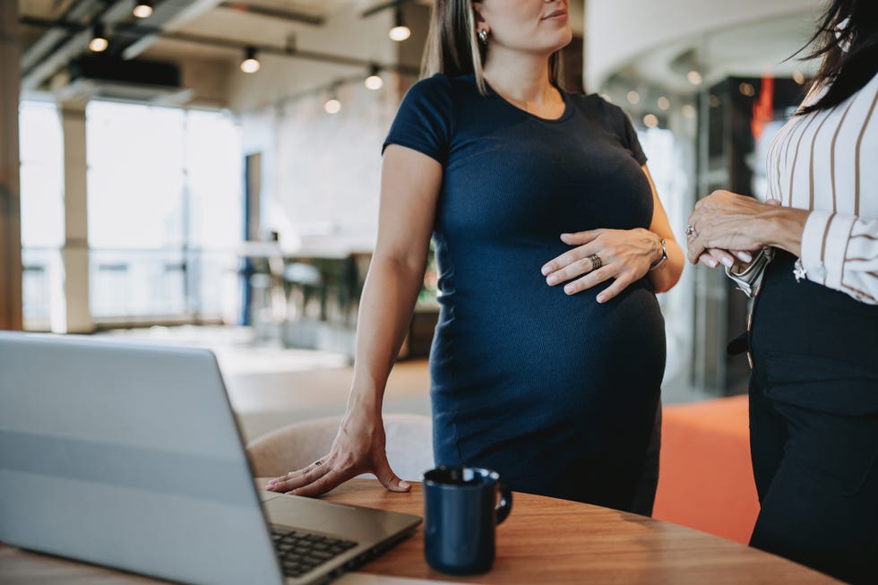 pregnant businesswoman talking to coworker