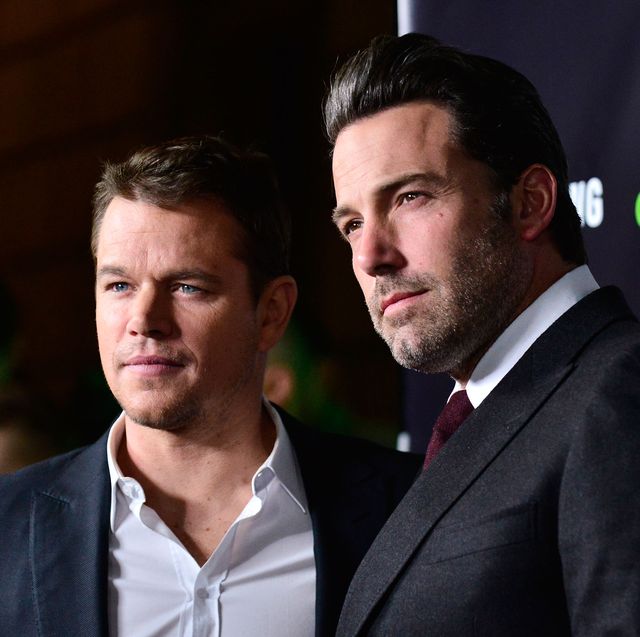 matt damon, wearing a blue suit jacket and no tie, stands with ben affleck, wearing a black suit and red tie