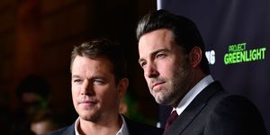 matt damon, wearing a blue suit jacket and no tie, stands with ben affleck, wearing a black suit and red tie
