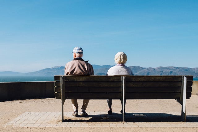 oude man en vrouw zitten op bankje met mooi uitzicht