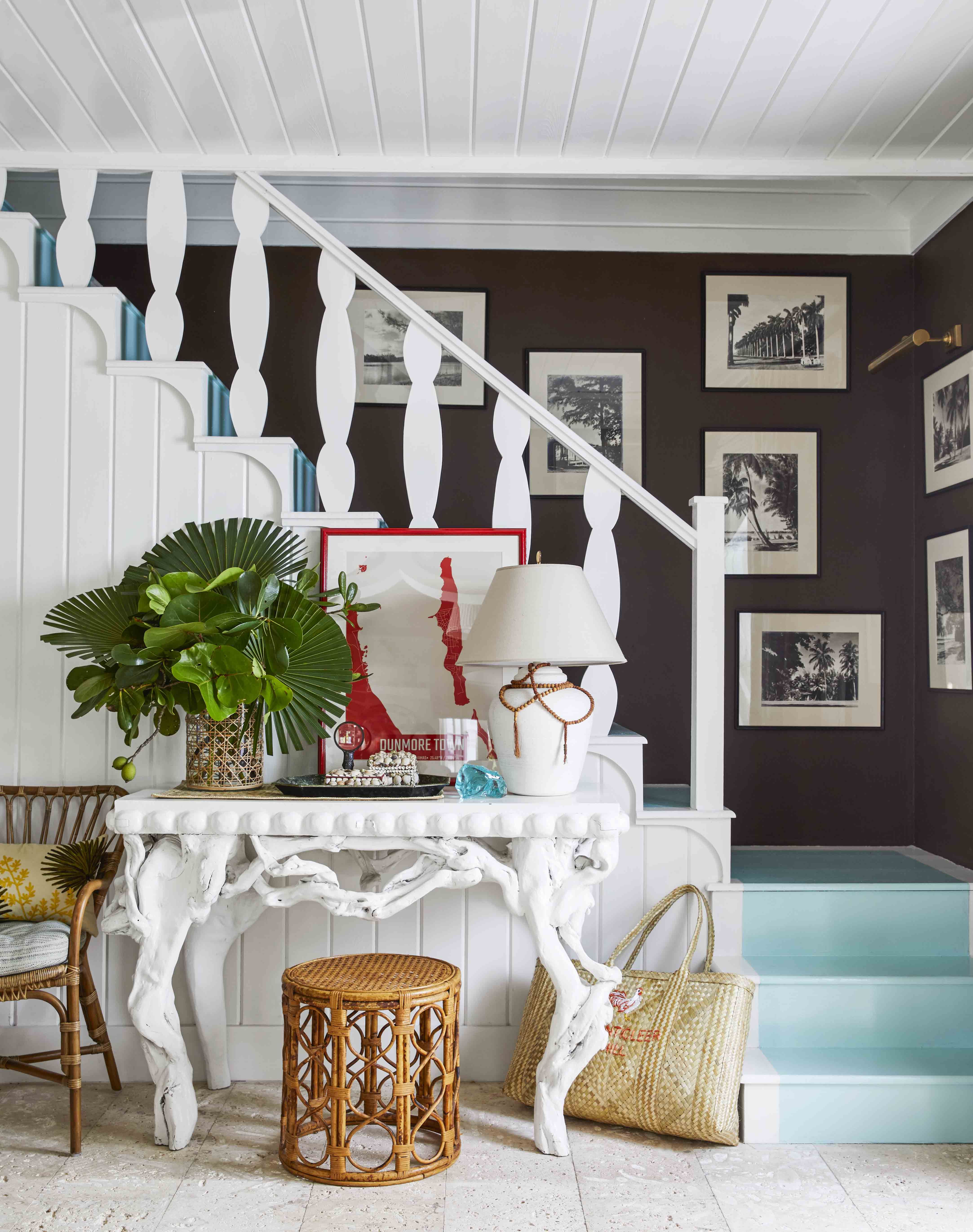 a stairwell painted white with a white table and a gallery wall in the backgroun