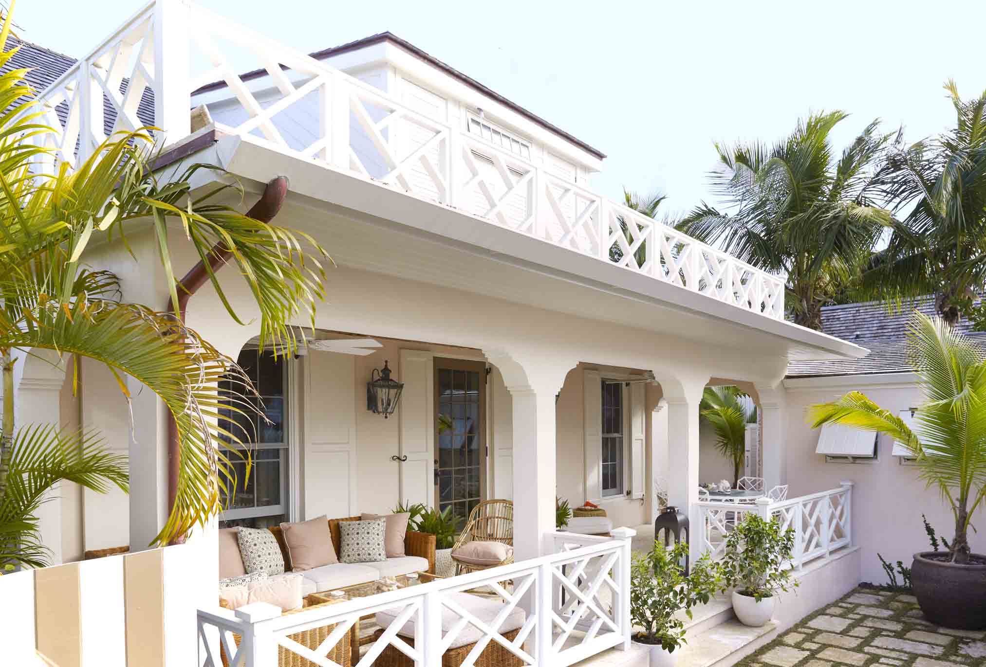a shell pink cottage in a tropical setting with white chippendale railings