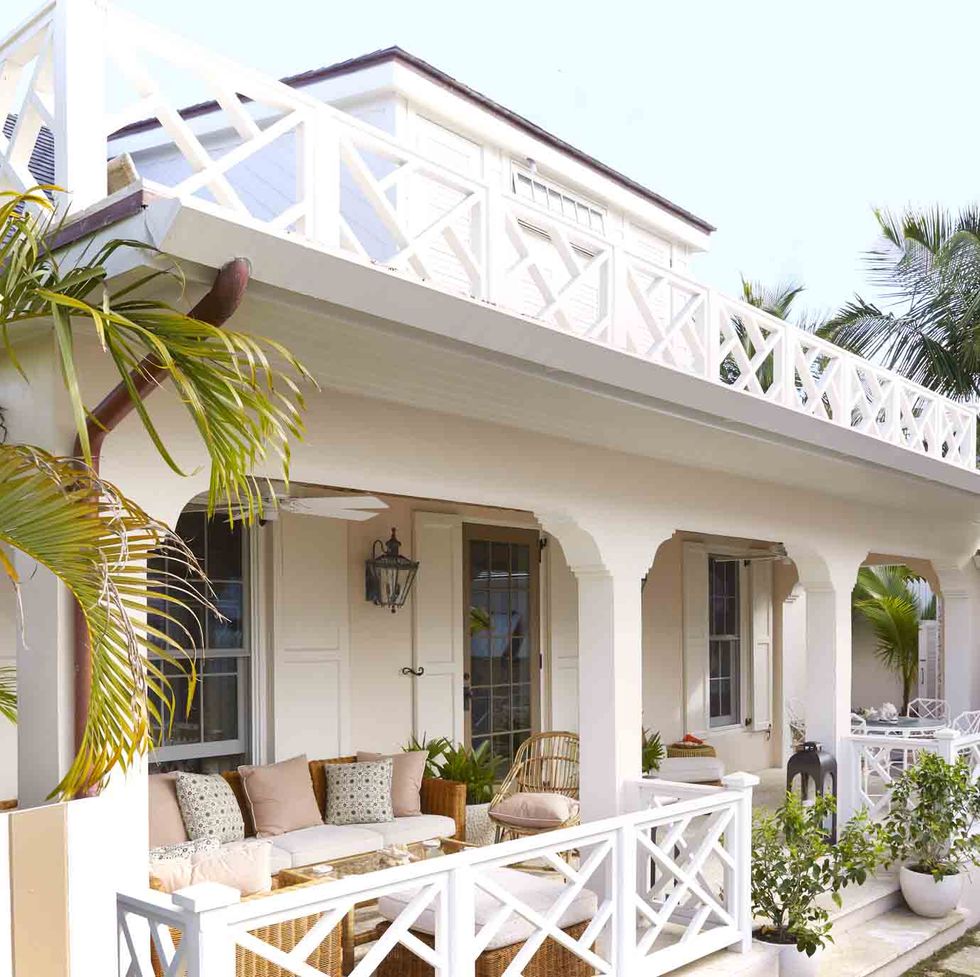 a shell pink cottage in a tropical setting with white chippendale railings