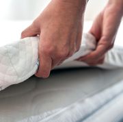 hands adjusting mattress topper on bed