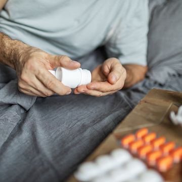 mature adult man lying down in bed and feeling sick, taking pills