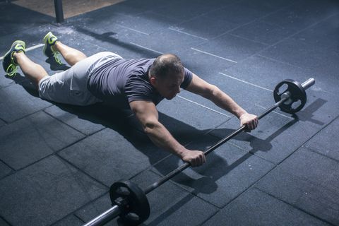 Mature athlete man doing exercise with weights in gym
