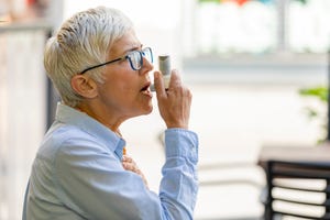 mature business woman using asthma inhaler