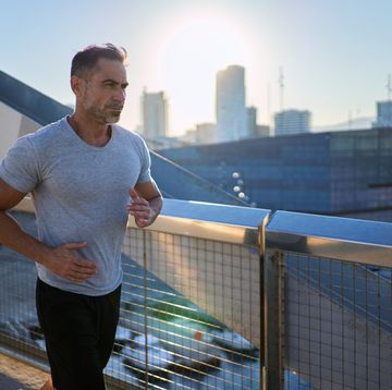 mature caucasian man running with the city on the background.
