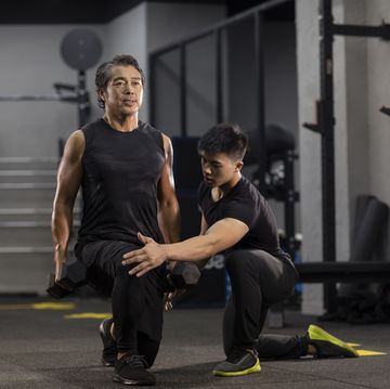 mature chinese man working out with personal trainer at gym