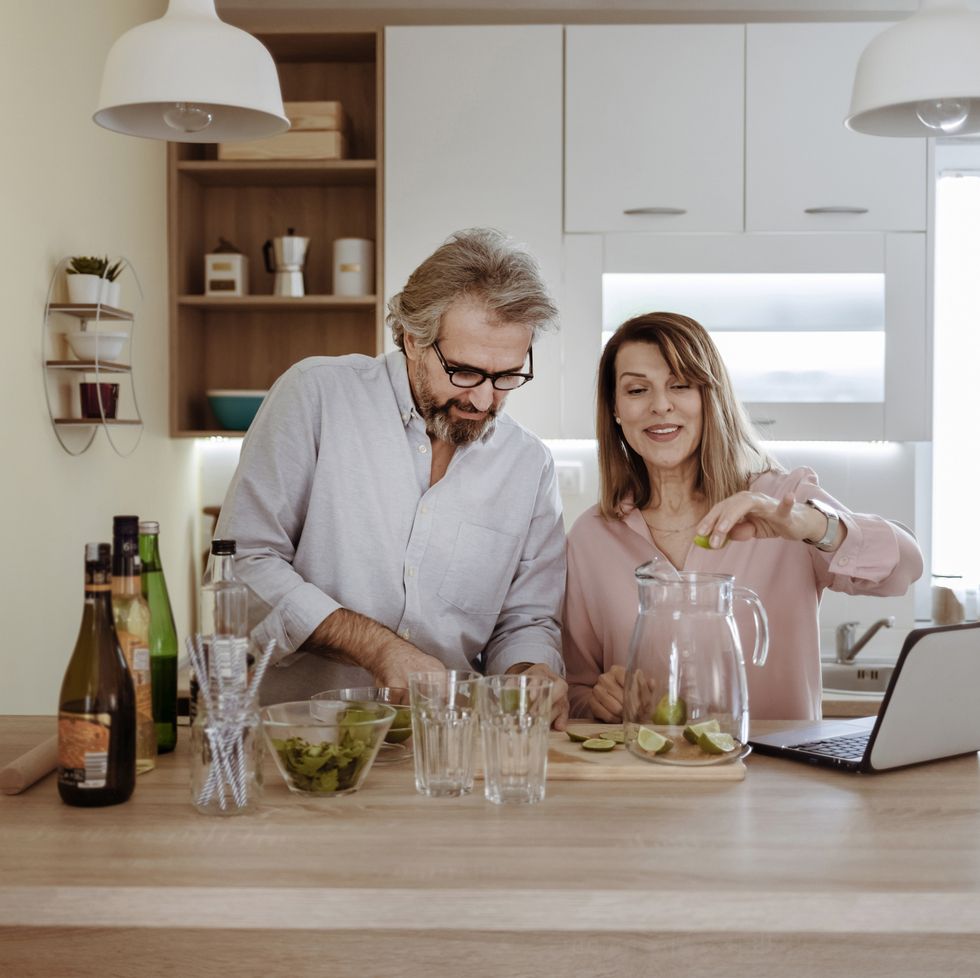 mature couple making cocktail while using laptop
